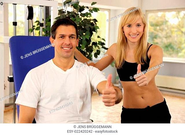 Attractive blonde woman and her trainer in a gym