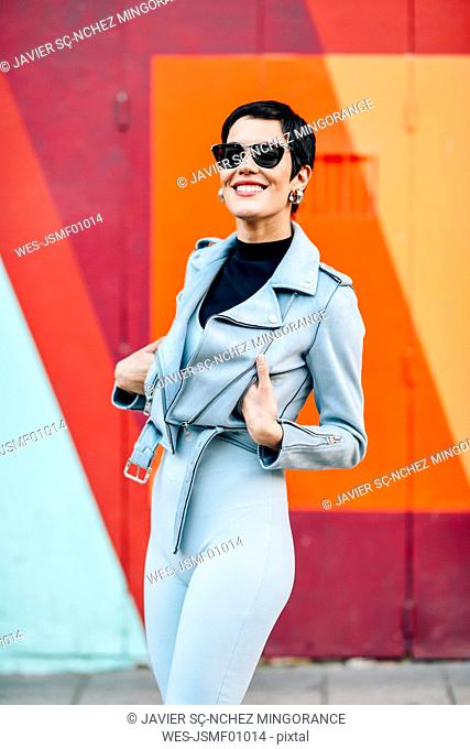 Smiling fashionable young woman with colorful urban background