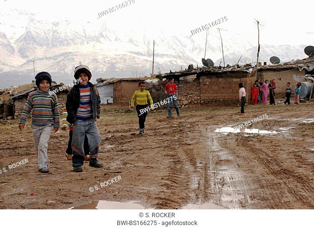 curious children in front of mud huts in a small kurdish village close to Amedi in northern Iraq in front of snowy mountains near the Turkish border, Iraq