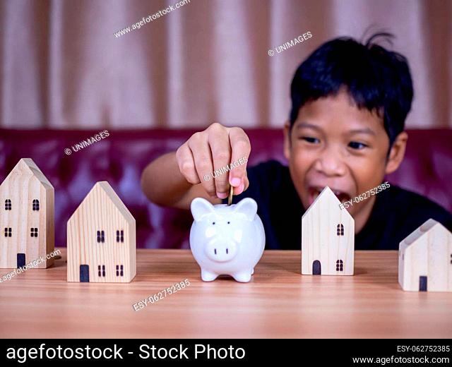 Boy saving money in a white pig piggy bank.Saving concept. Saving for the future