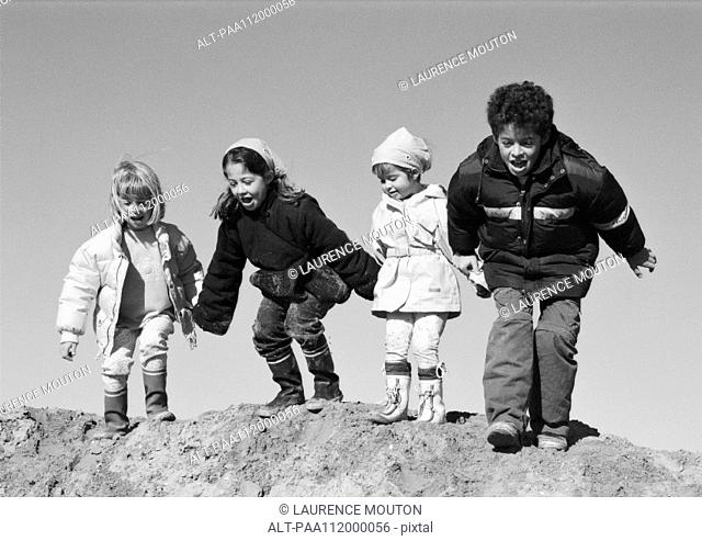 Three girls and boy holding hands, preparing to jump, b&w