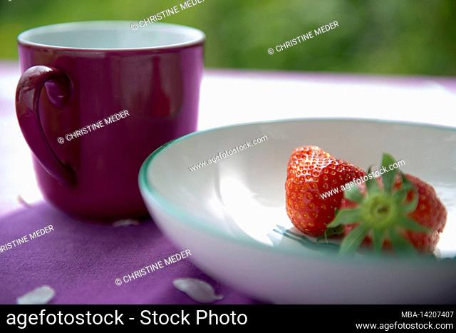two strawberries, cup, table