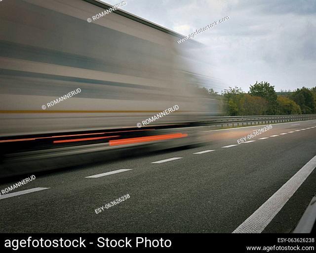A truck driving on the highway at dusk. Motion blur on the highway. Evening shot of a truck. Concept of international transport and logistics