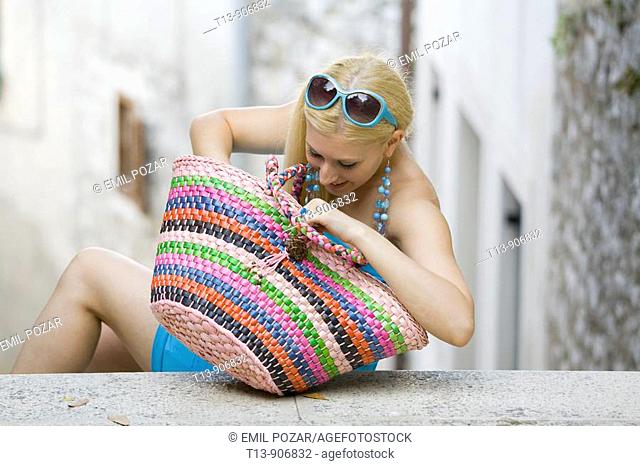 Young woman is searching in big colourful bag