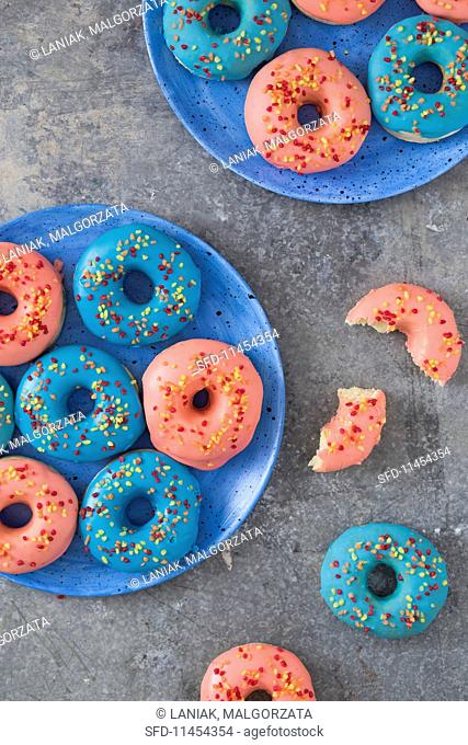 Doughnuts with pink and blue icing and sugar sprinkles (seen from above)