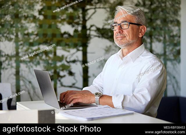 Businessman contemplating while working on laptop in office