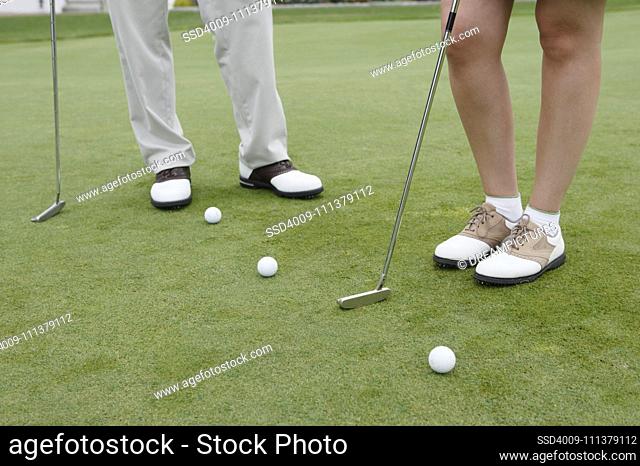 Low section of couple's feet playing golf