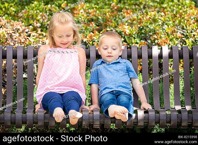 Young sister and brother having fun on the bench at the park