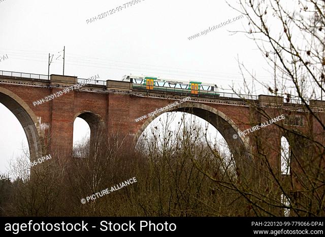 17 January 2022, Saxony, Barthmühle: A train drives over the Elster Valley Bridge. Water penetrates the masonry of the 150-year-old stone bridge