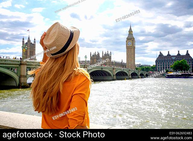 Tourism in London. Back view of traveler girl enjoying sight of Westminster bridge and palace on River Thames with famous Big Ben tower in London, UK
