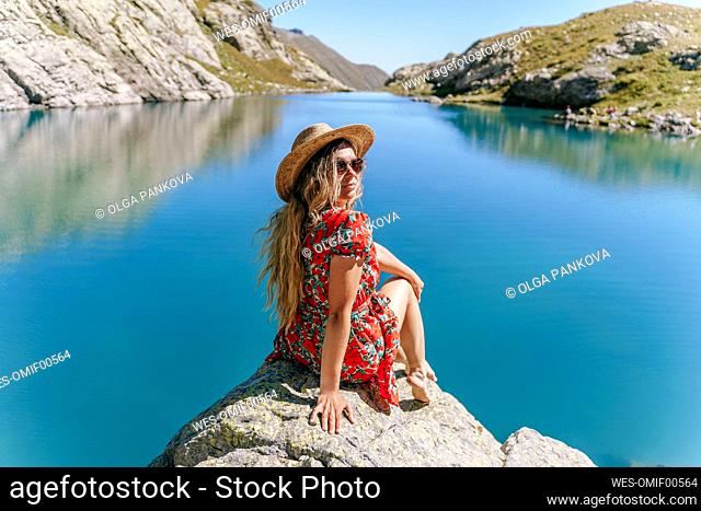 Woman sitting on rock by lake, Sochi, Russia