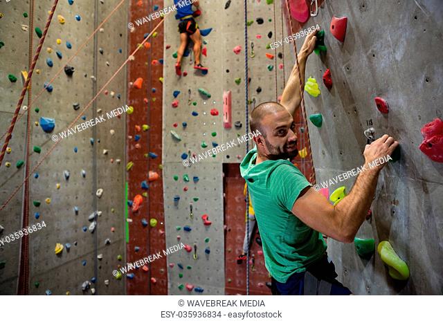 Portrait of male athlete climbing wall in health club