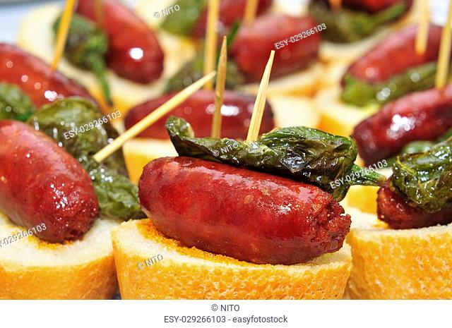 closeup of a plate with spanish pinchos made with chorizos an Padron peppers