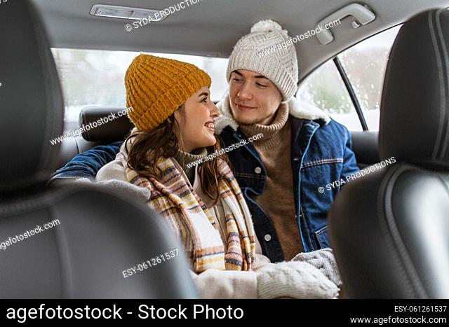 happy smiling couple on car back seat in winter