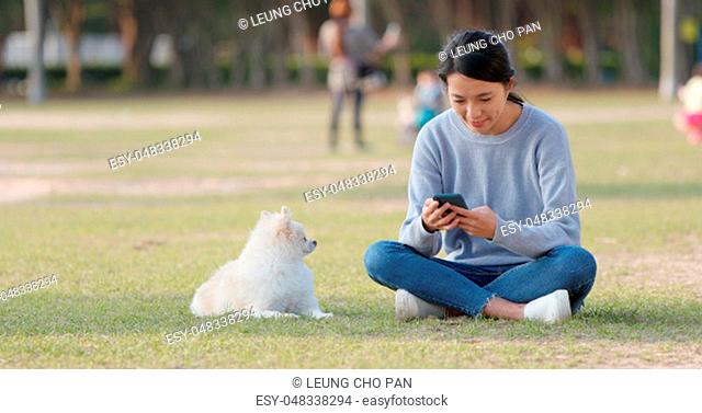 Woman use of smart phone with her dog at outdoor park