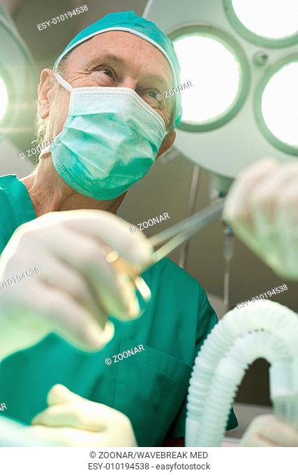 Surgeon smiles as he takes a surgical scissors
