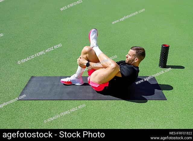 Athlete stretching on exercise mat on sunny day