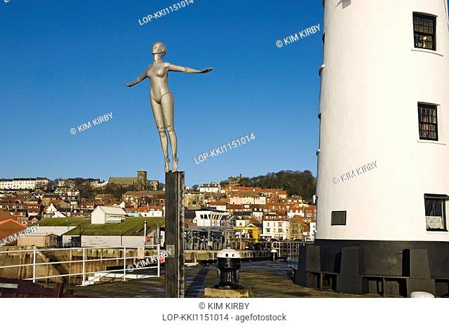 England, North Yorkshire, Scarborough, The Diving Belle sculpture representing Scarborough of the present by Craig Knowles next to Scarborough Lighthouse on...