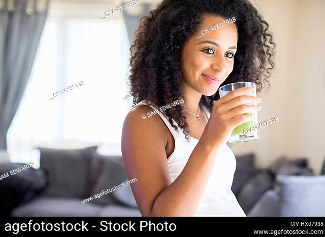 Happy young pregnant woman drinking green smoothie