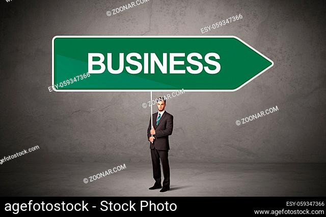 Young business person in casual holding road sign with BUSINESS inscription, new business direction concept