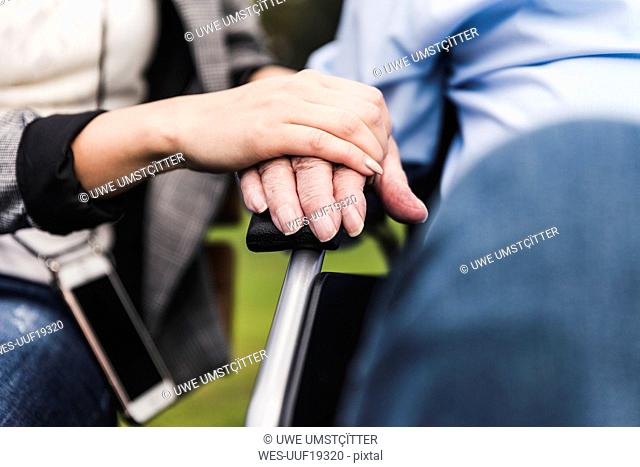Young woman touching senior man's hand, close-up