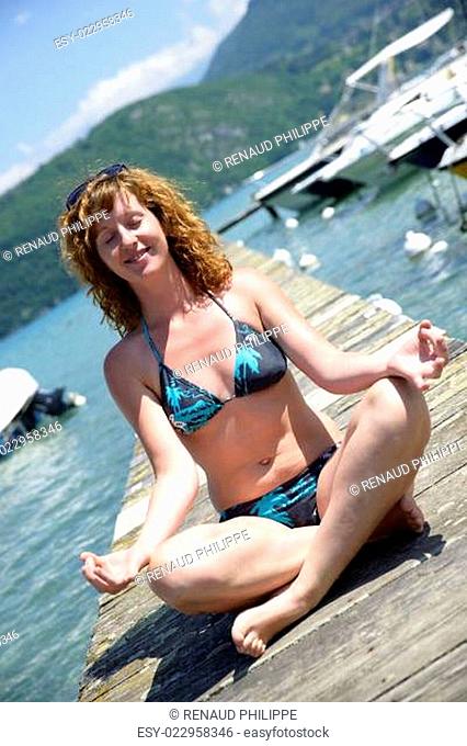 redhead young woman doing yoga on the waterside