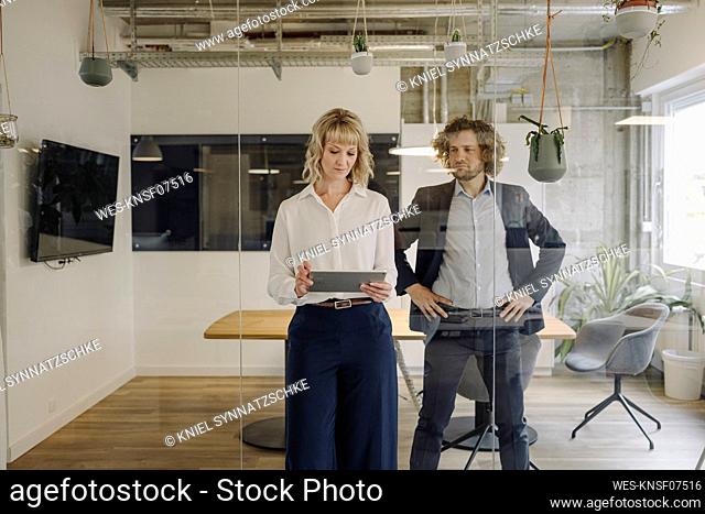 Businessman and businesswoman using tablet in office