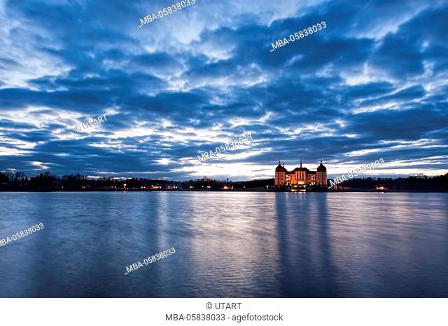 View to the illuminated castle Moritzburg, Saxony, in the early evening hours, blue hour with unusual beautyful clouds