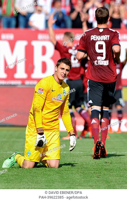 Bremen's keeper Sebastian Mielitz looks disappointed after the 2-1 goal for Nuremberg, while goal scorer Sebastian Polter (back) cheers during the Bundesliga...