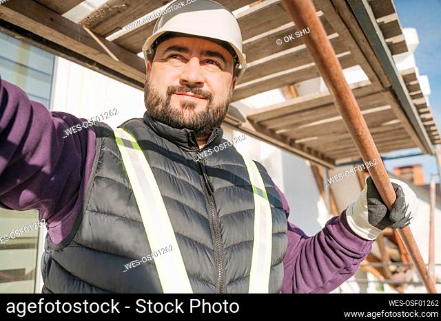 Construction worker holding metal rebar in front of house