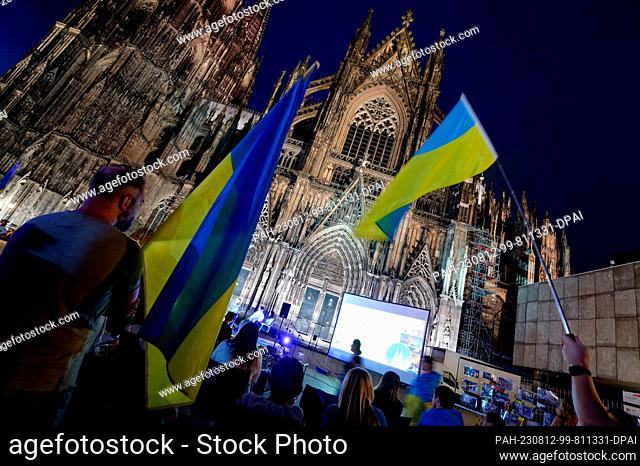 11 August 2023, North Rhine-Westphalia, Cologne: Participants stand in front of the cathedral at the event ""Unbreakable Ukraine - Night Rally for the Future of...