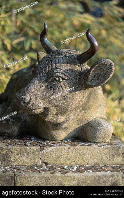 Buddhist stone statue of a bull lying with coins placed as an offering on his base in the Enryaku temple of Ryôgen monk in Hiei Mountain near Kyoto, Japan