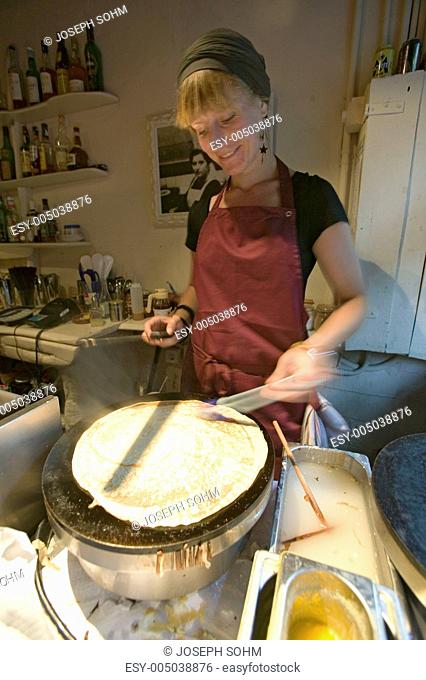 Young female chef prepares crepes in French restaurant in old section of Barcelona, Spain