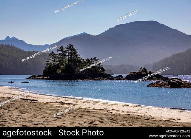 Two kayakers paddle pass an Islet at Benson Point on Nootka Island, Nuchatlitz Provincial Park, British Columbia, Canada
