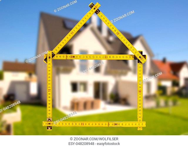 Hausbau und Verkauf mit Meterstab als Symbol