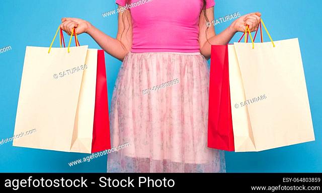 Portrait of young happy smiling woman with shopping bags, over blue background. Purchase, sale and people concept