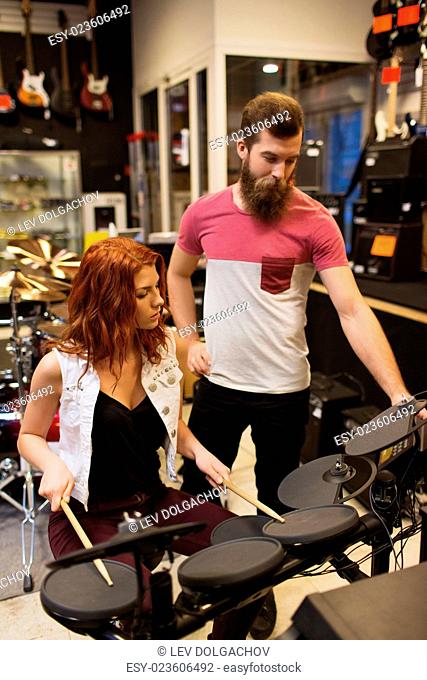 music, sale, people, musical instruments and entertainment concept - man and woman with drum kit at music store