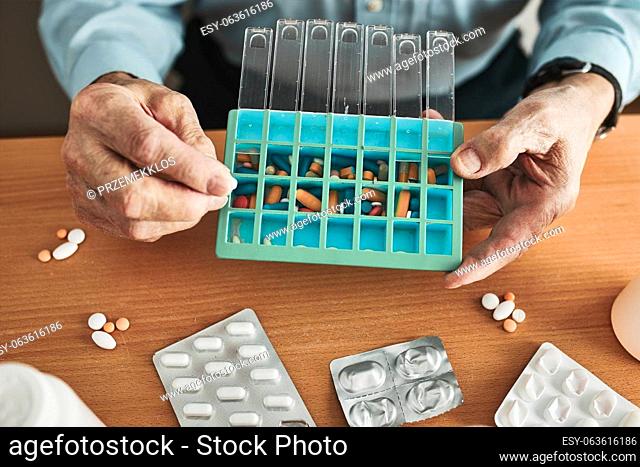 Senior man organizing his medication into pill dispenser. Senior man taking pills from box. Healthcare and old age concept with medicines
