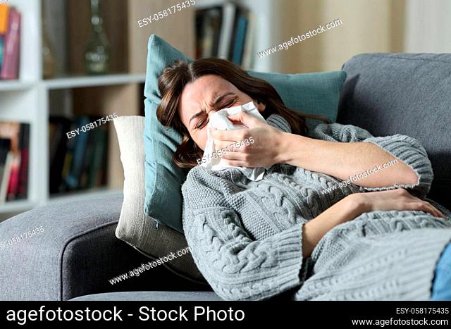 Ill woman suffering flu symptoms blowing on tissue
