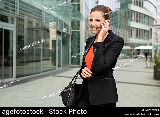 Young businesswoman on the phone in front of an office building