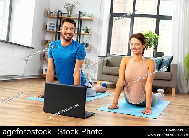 happy couple with laptop exercising at home
