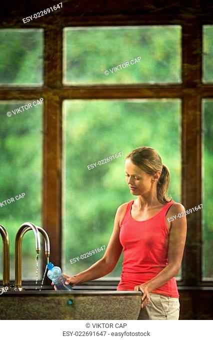 Young woman fillig a plastic bottle with healthy mineral water