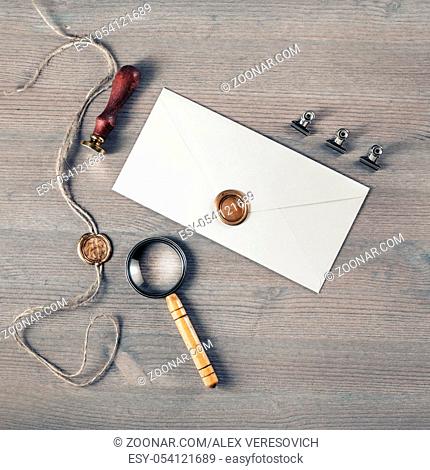 Blank envelope, stamp and magnifier on wooden background. Flat lay