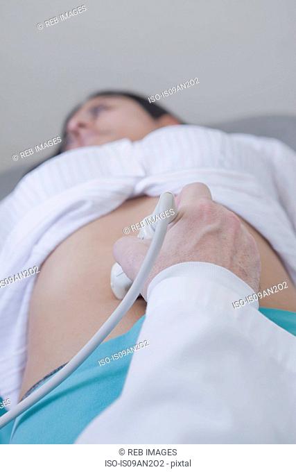 Hand of sonographer using transducer on womans stomach