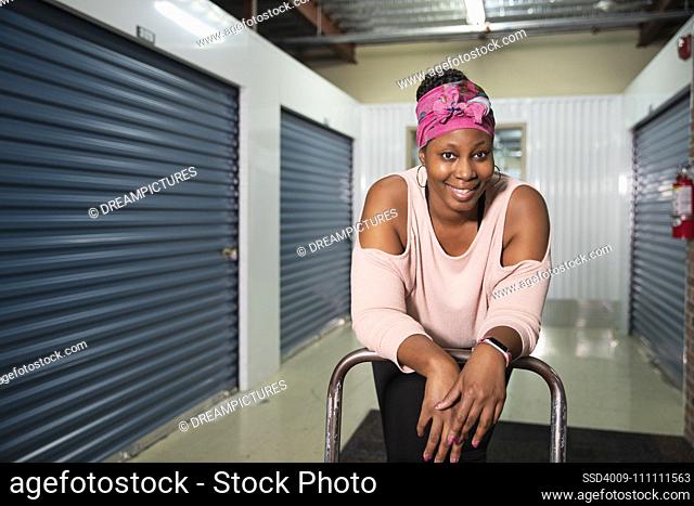 Portrait of a woman leaning over a cart inside a storage facility