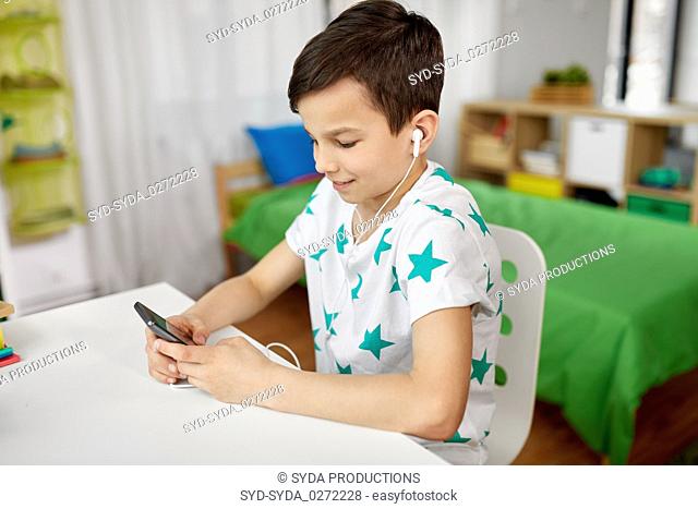 boy in earphones listening to music on smartphone