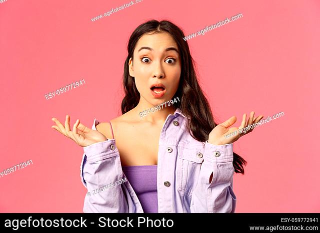 Close-up portrait of speechless, impressed young asian woman, spread hands sideways, gasping and open mouth wide from amazement, see something incredible