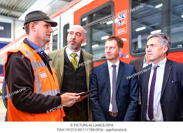 11 December 2019, Saxony, Bautzen: Bombardier employee Mike Herbrich (left) explains the so-called wheel upright measurement to the Saxon Prime Minister Michael...