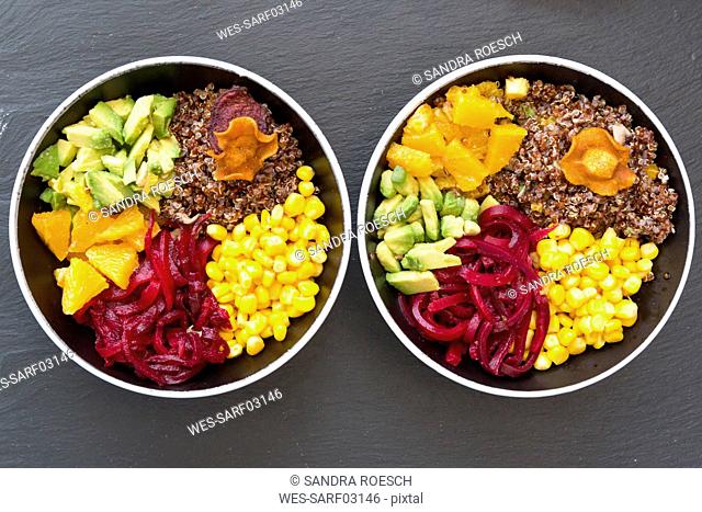 Two lunch bowls of red quinoa, beetroot, corn, avocado, orange and vegetable chips