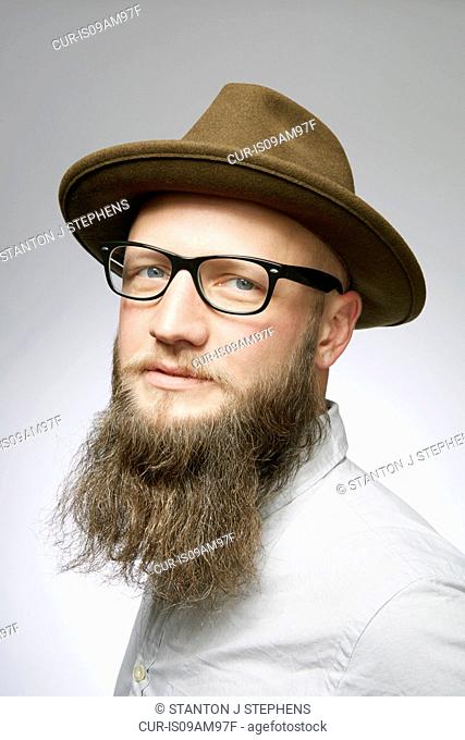 Studio portrait of mid adult man in trilby with overgrown beard